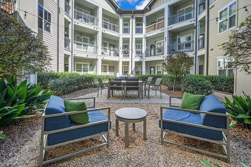A patio with blue cushions and a table surrounded by plants.